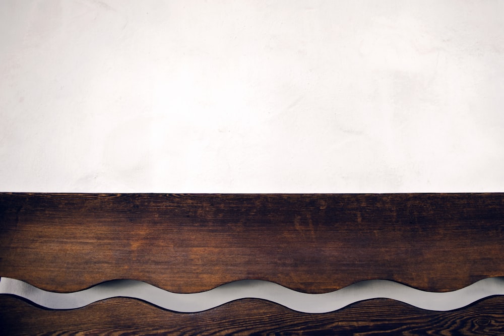 a close up of a wooden bench with a white wall in the background