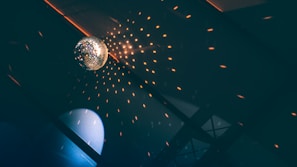 A playful shot of a disco ball hanging low, reflecting tiny light dots onto smiling faces in the crowd.
