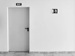 closed white painted door with exit signage