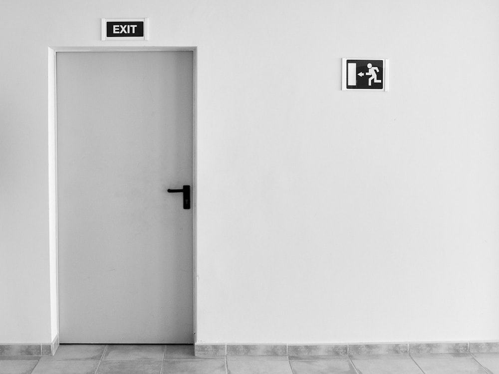 closed white painted door with exit signage