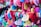 A vibrant collection of colorful love locks attached to a fence. Heart-shaped locks are inscribed with handwritten messages in various languages, creating a kaleidoscope of colors including red, pink, blue, green, and yellow.