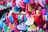 A vibrant collection of colorful love locks attached to a fence. Heart-shaped locks are inscribed with handwritten messages in various languages, creating a kaleidoscope of colors including red, pink, blue, green, and yellow.