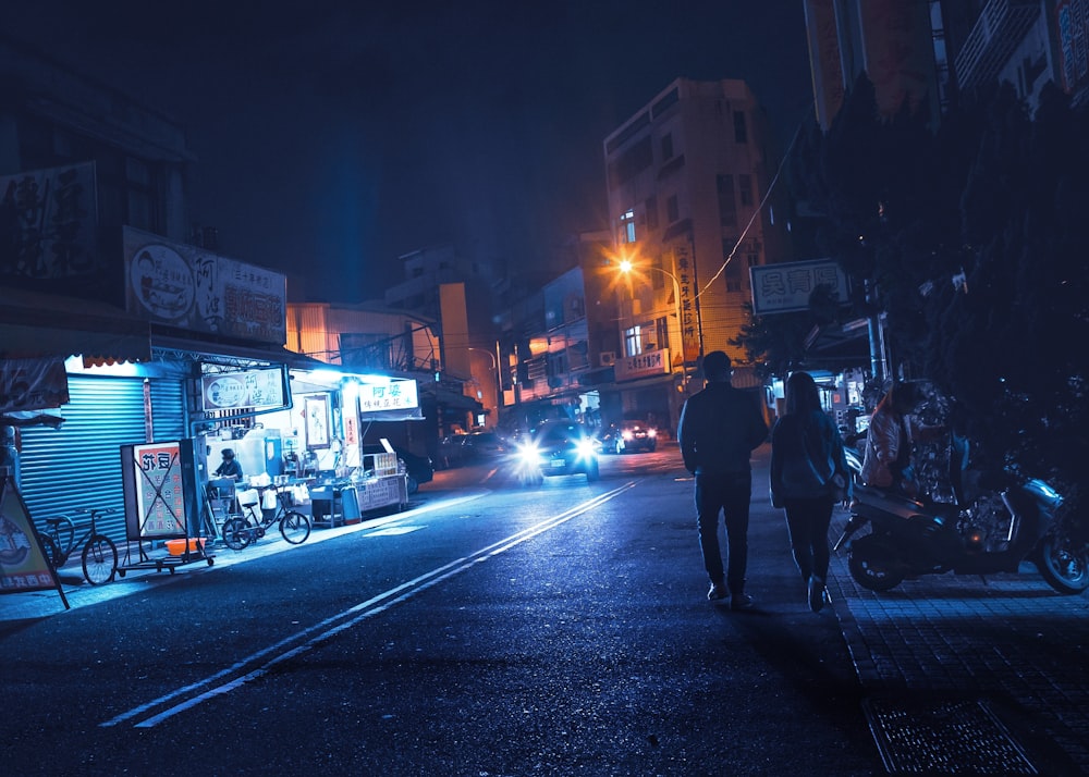 man and woman walking on road near building