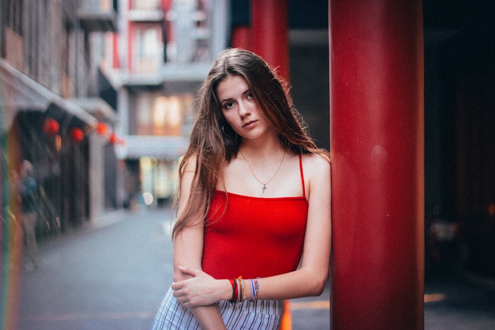 woman leaning on red concrete pillar during daytime