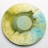 A vinyl record with a marbled design of yellow, green, and blue swirls, centered on a plain background.