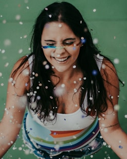 A close-up of a smiling guest mid-spin, hair and confetti swirling around them in the photobooth.