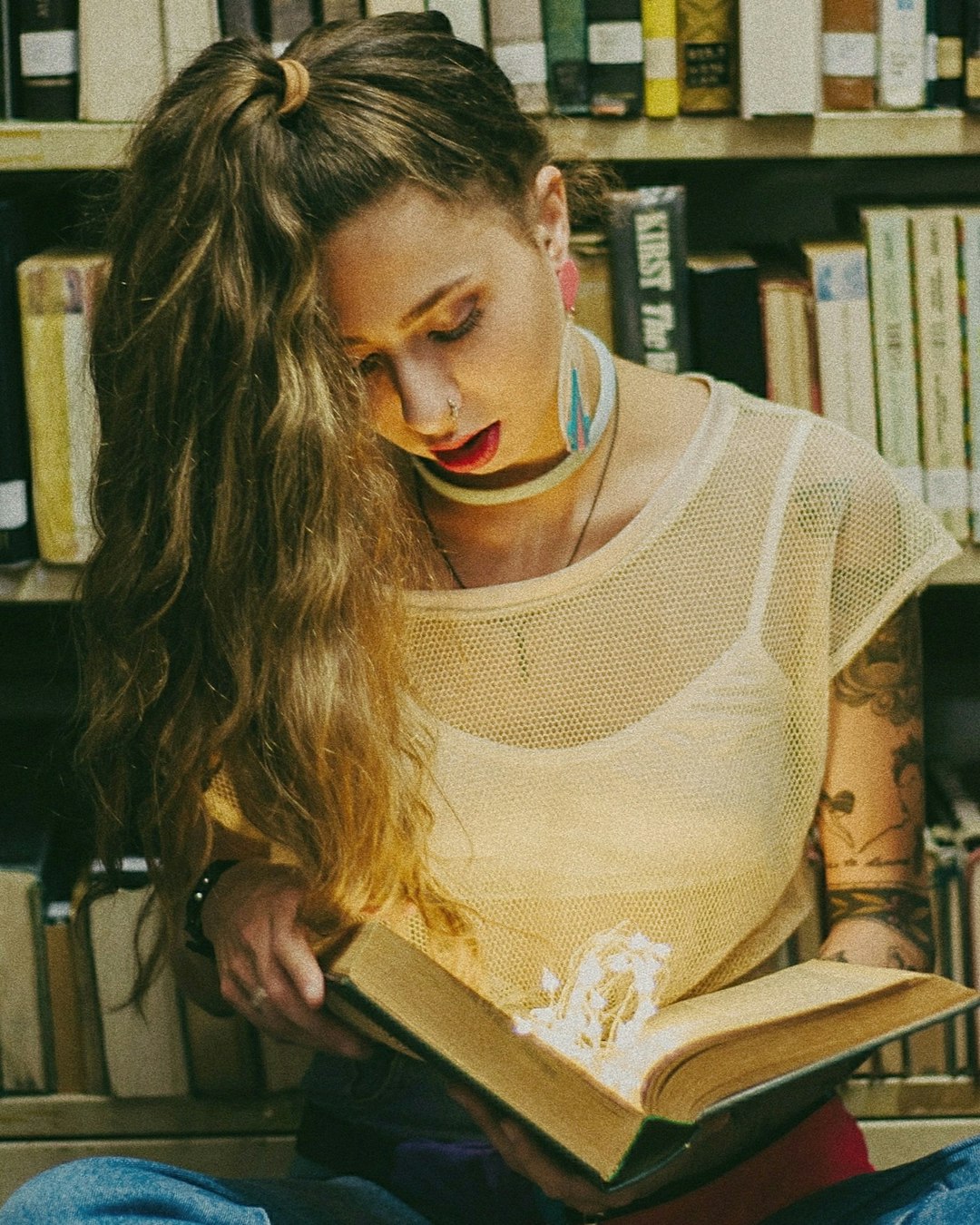 woman wearing white spaghetti strap dress reading book inside library