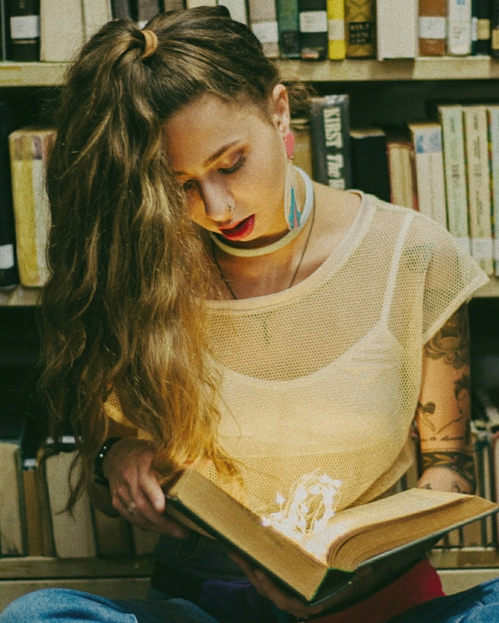 woman wearing white spaghetti strap dress reading book inside library