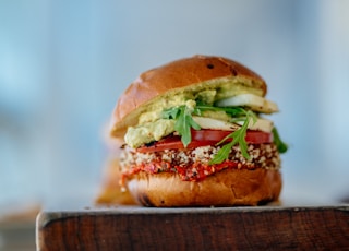 selective focus photography of hamburger with sliced tomatoes and vegetables