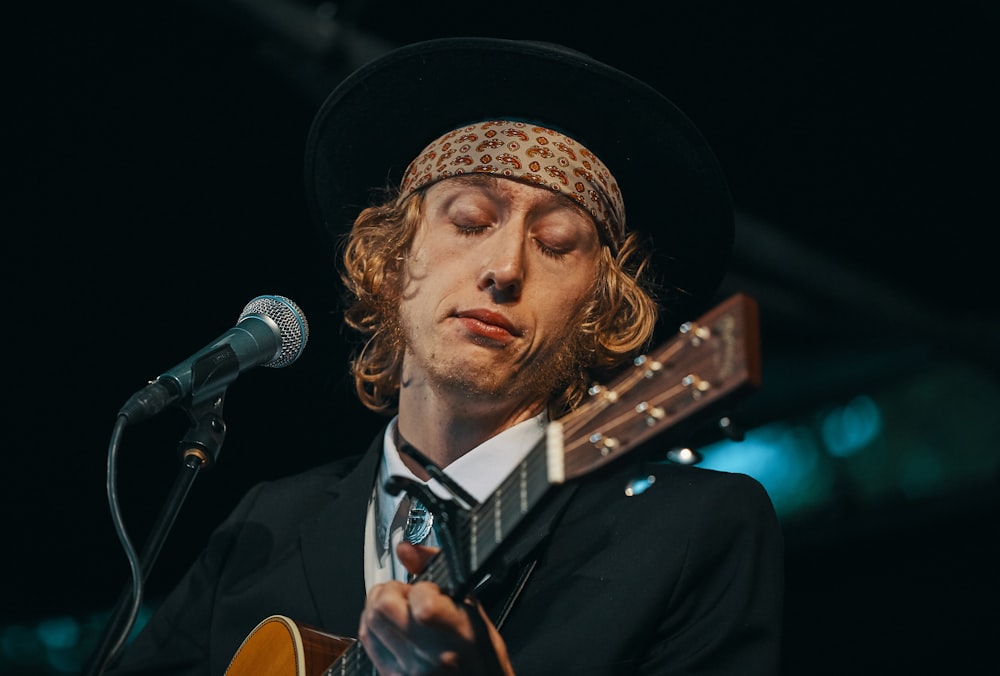 man playing brown guitar