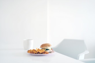Overhead shot of a minimalist table setting with burgers wrapped in paper and a soft pastel background