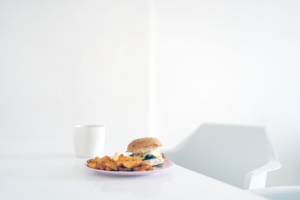 Overhead shot of a minimalist table setting with burgers wrapped in paper and a soft pastel background