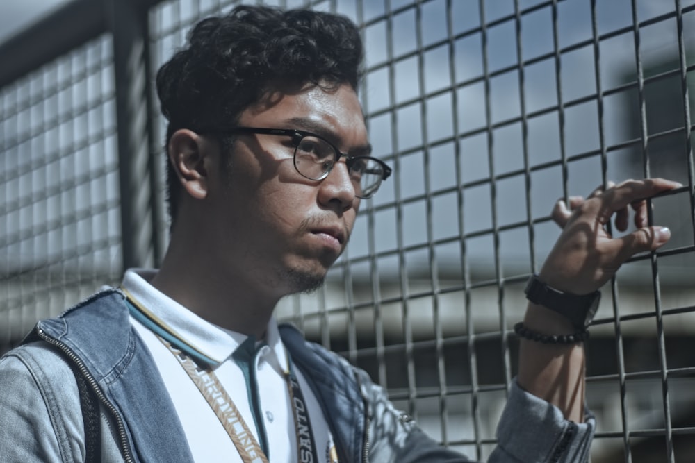 man wearing eyeglasses near the fence