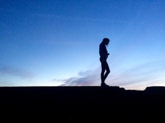 A silhouette of a woman standing by a balcony at dusk, capturing a mood of contemplation and freedom.
