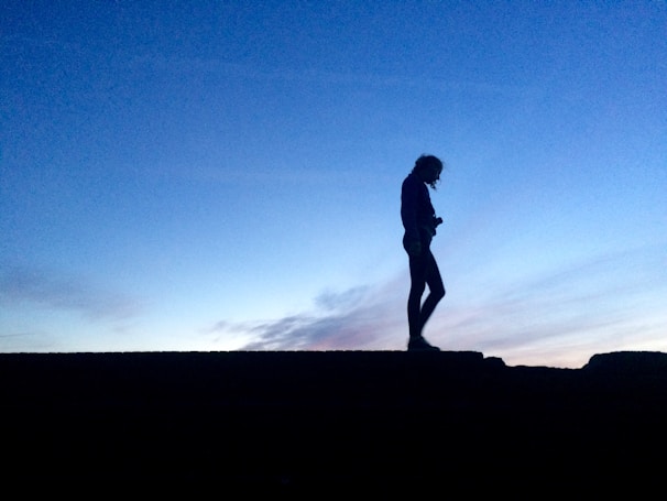A silhouette of a woman standing by a balcony at dusk, capturing a mood of contemplation and freedom.