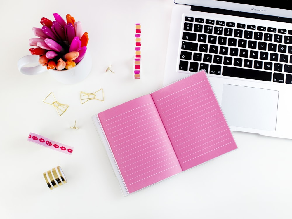 pink lined notebook beside MacBook Air