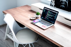 smartphone on laptop computer on top of brown wooden desk