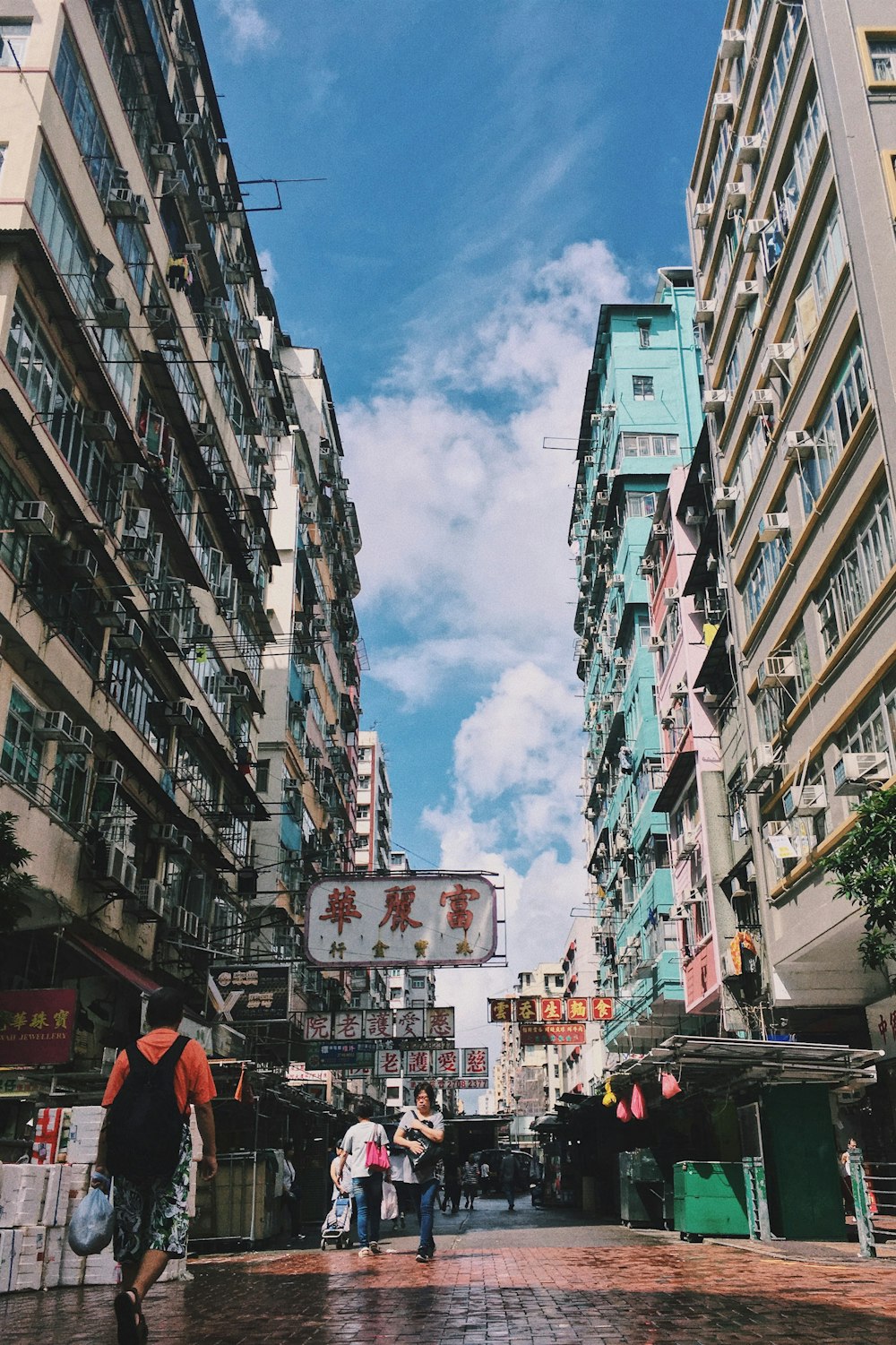 man walking in street while carrying plastic bag and backpack