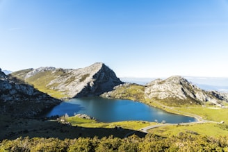A serene landscape featuring a tranquil lake surrounded by mountains under a clear blue sky.