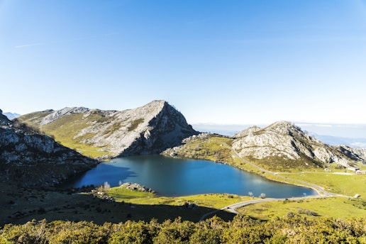 A serene landscape featuring a tranquil lake surrounded by mountains under a clear blue sky.