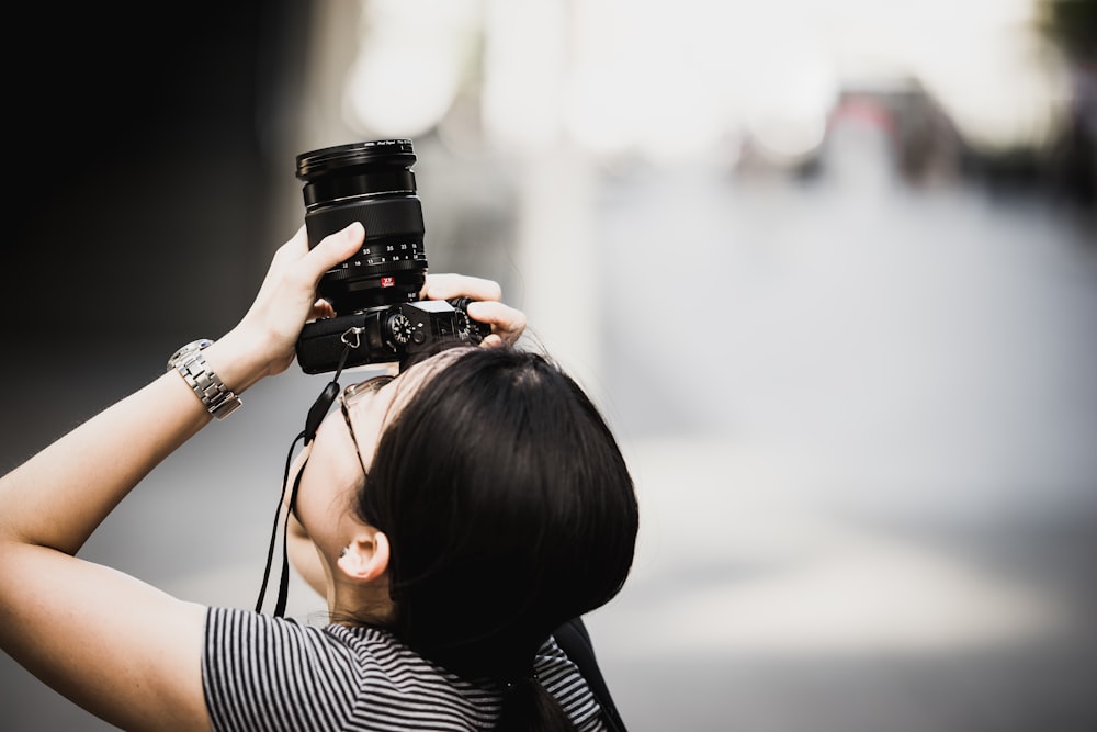 woman holding DSLR camera while focusing on top