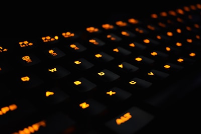 Close-up of hands typing on a keyboard with vibrant orange accents glowing softly.