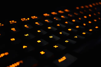 Close-up of hands typing on a backlit mechanical keyboard with vibrant orange accents.