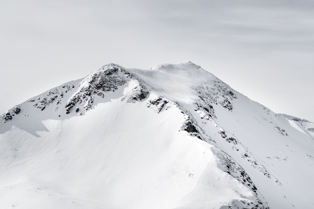 mountain covered with snow under white clouds