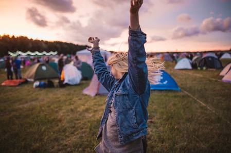 a woman raising her arms in the air in front of tents