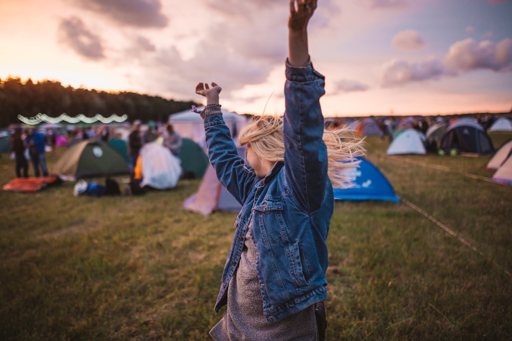 a woman raising her arms in the air in front of tents