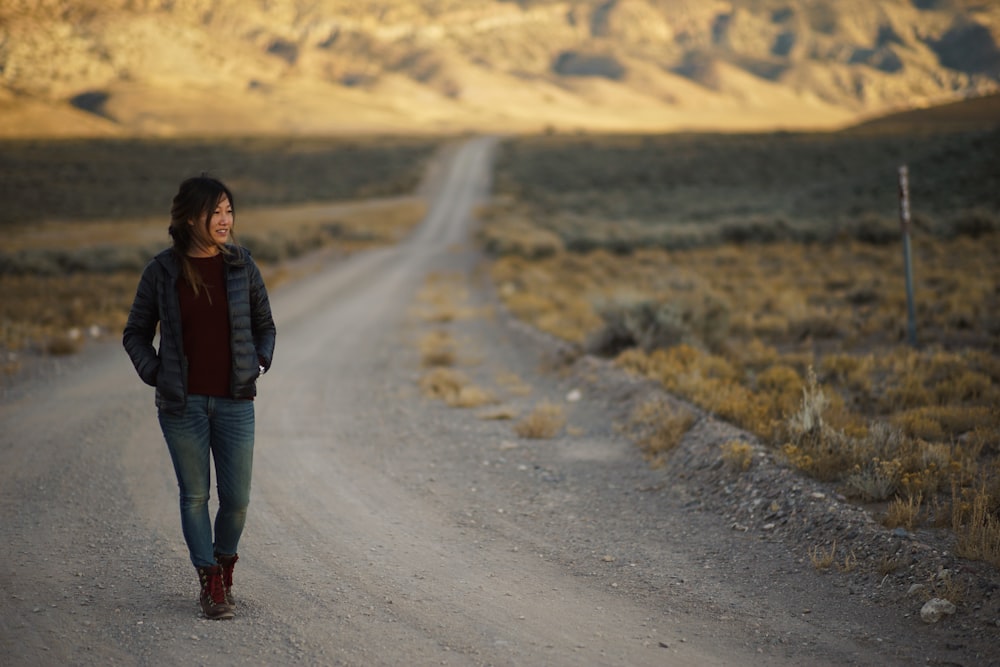 man walking on gray soil road