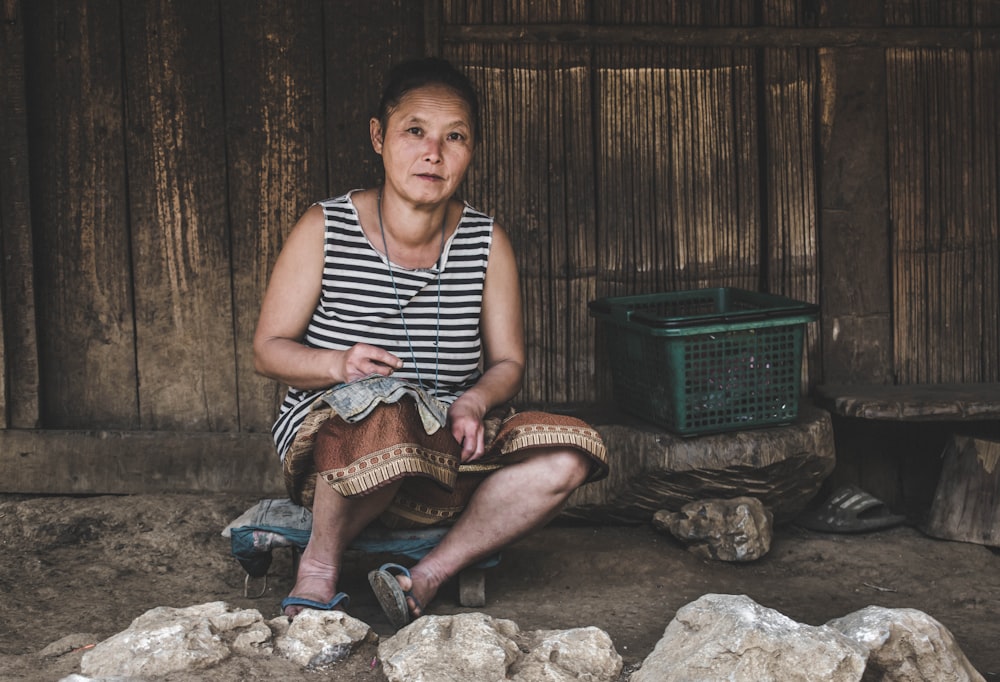 woman sitting near green plastic basket outside