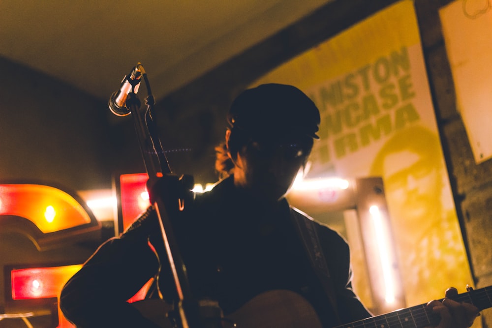 man playing guitar near corded microphone