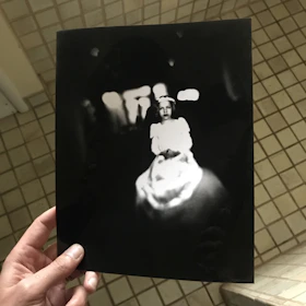 Close-up of hands holding a mysterious old photograph with cryptic notes around it.