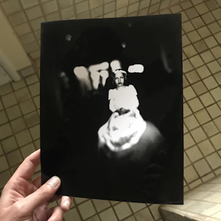 Close-up of hands holding a mysterious old photograph with cryptic notes around it.