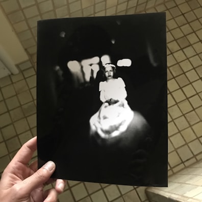 A close-up of a hand holding a faded photograph.