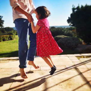 A child and adult happily hopping together on a bright mat outdoors.