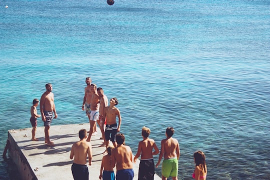 group of people playing ball on wooden dock in Agios Stefanos Beach Greece