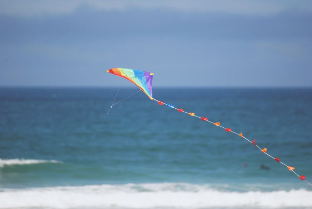 photo of multicolored kite flying beside seashore