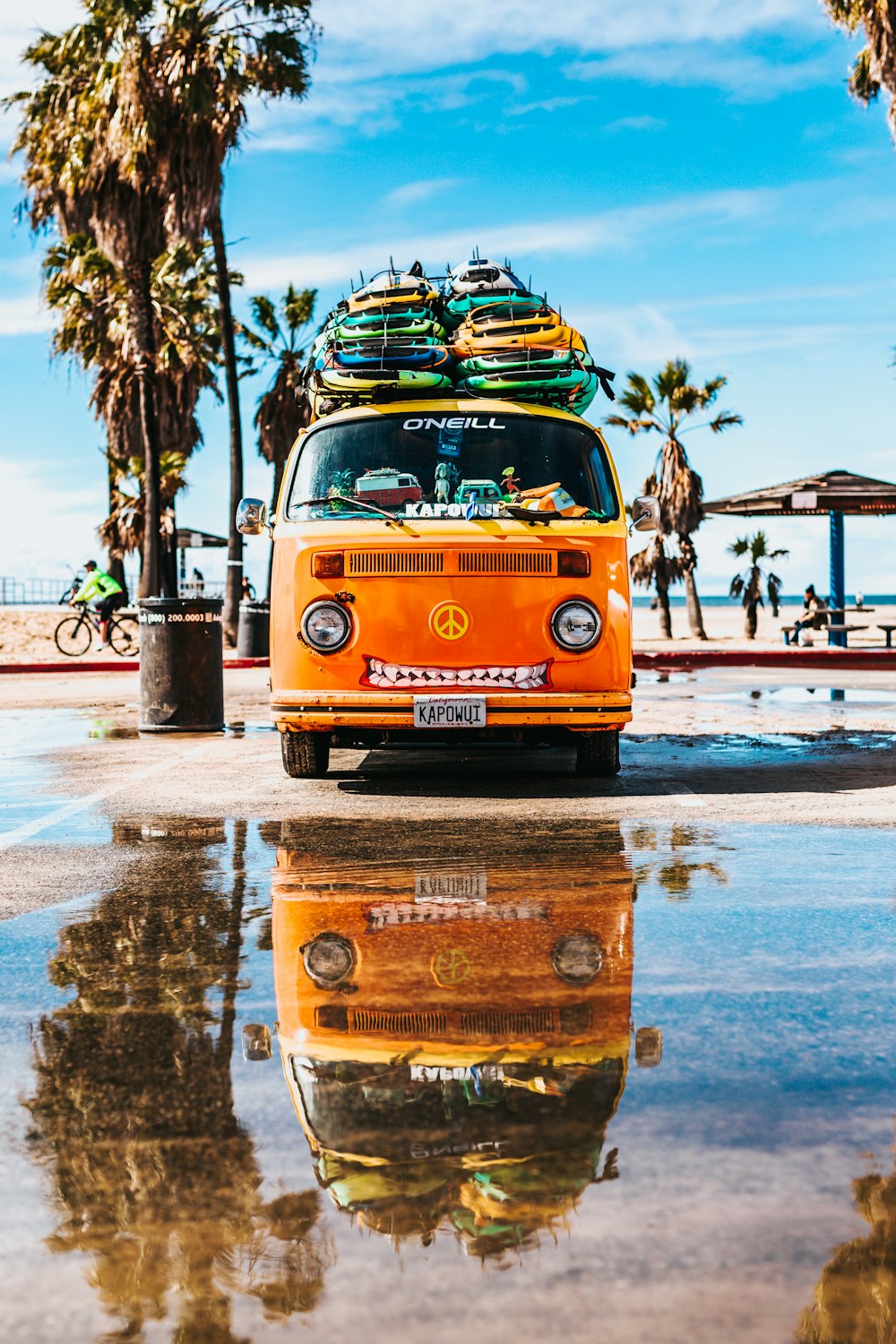 furgoneta naranja con tabla de surf en la parte superior