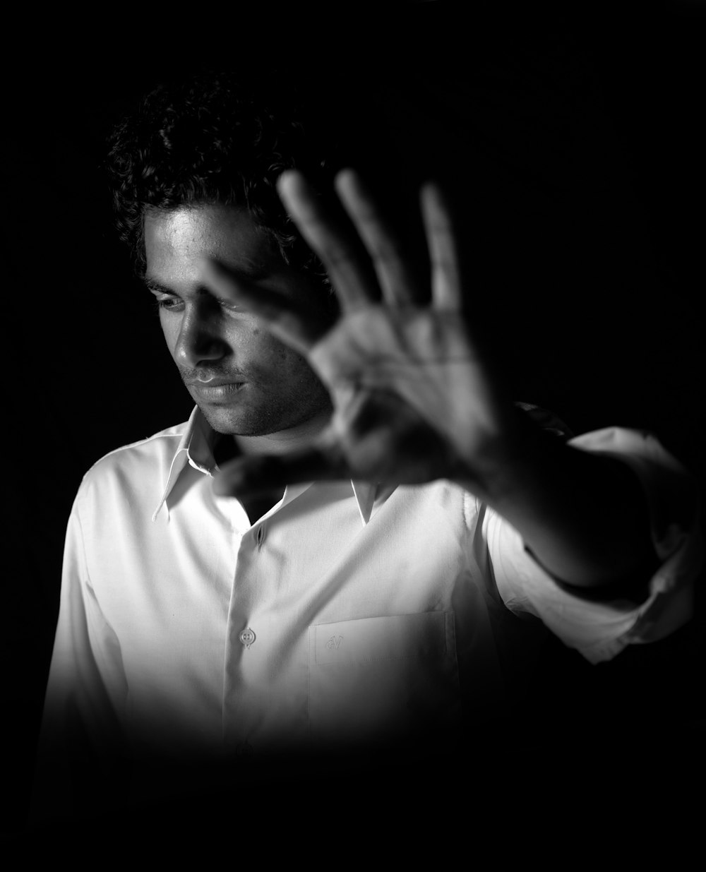 grayscale photograph of man in dress shirt raising his left hand