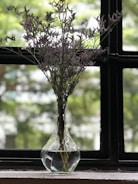 A delicate ceramic vase with hand-painted floral designs sitting on a windowsill.