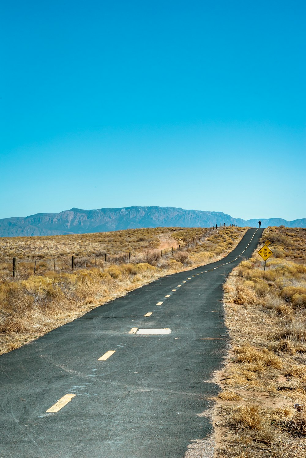 road with brown grass under blue skies