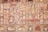 The image features a richly decorated, ornate wall showcasing intricate patterns and faded frescoes. The design consists of repetitive geometric shapes and floral motifs in a variety of earthy tones. The top section includes small, lattice-covered windows.