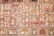 The image features a richly decorated, ornate wall showcasing intricate patterns and faded frescoes. The design consists of repetitive geometric shapes and floral motifs in a variety of earthy tones. The top section includes small, lattice-covered windows.