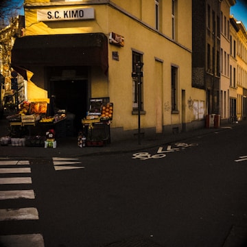 A bright storefront of a neighborhood convenience shop with fresh produce displayed outside.