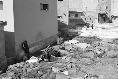 Wide shot of an outdoor ruined space with actors positioned in fragmented light patches.