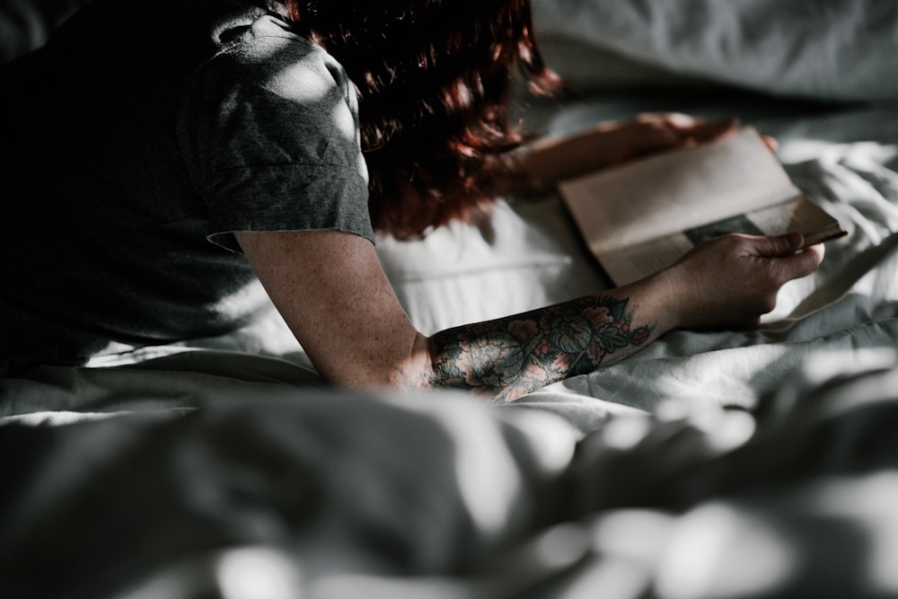 a woman laying in bed reading a book