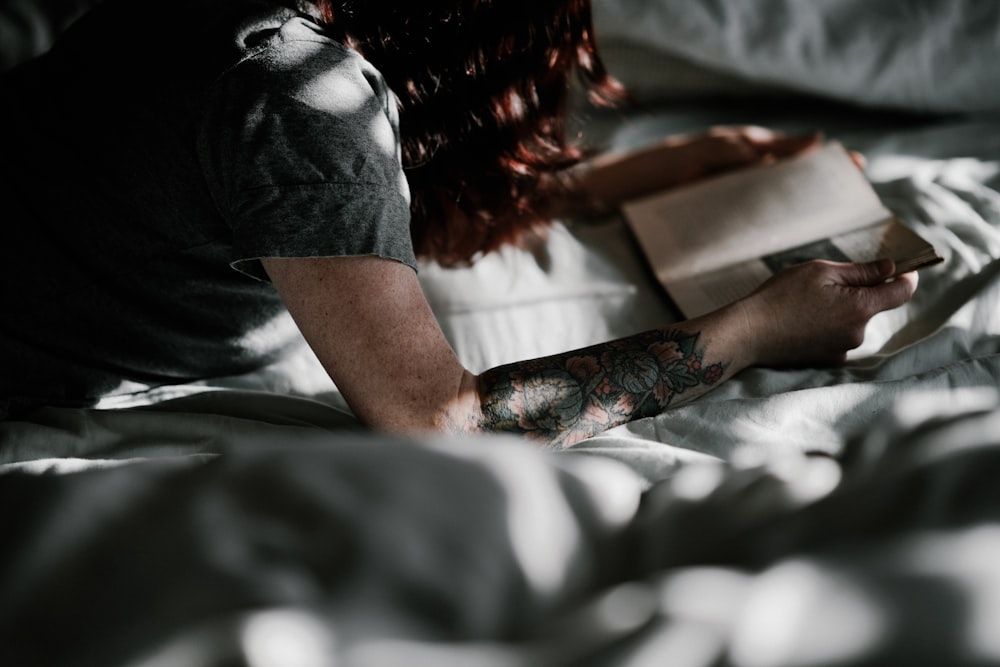 uma mulher deitada na cama lendo um livro