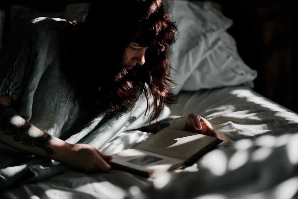 woman reading book on bed